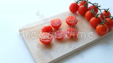 成熟的红小樱桃西红柿成串，部分切在厨房板和白色背景